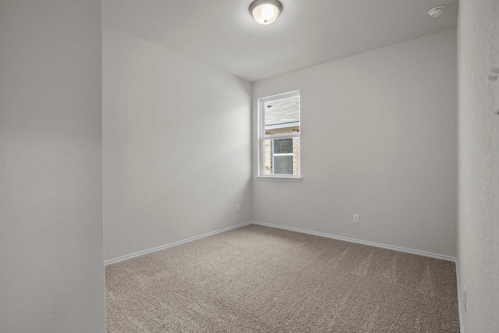 Cozy secondary bedroom with neutral walls, beige carpet, and window AC unit in Davidson Homes The Redbud B, Josephine, Texas