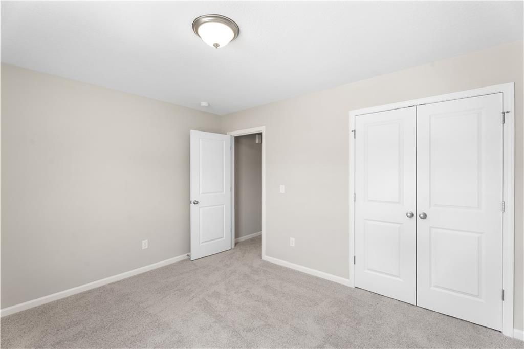Spacious secondary bedroom with beige walls, white double closet doors, and carpeted floor in Davidson Homes The Washington, Phenix City