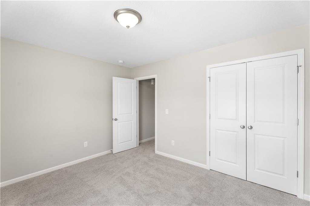 Spacious secondary bedroom with beige walls, white double closet doors, and carpeted floor in Davidson Homes The Washington, Phenix City