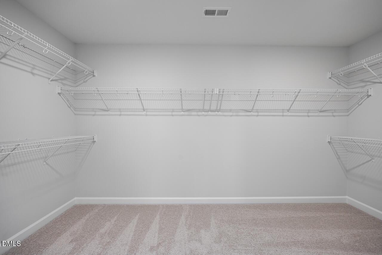 Spacious walk-in closet with white wire shelving and beige carpet in Davidson Homes The Hickory II B, Zebulon, NC