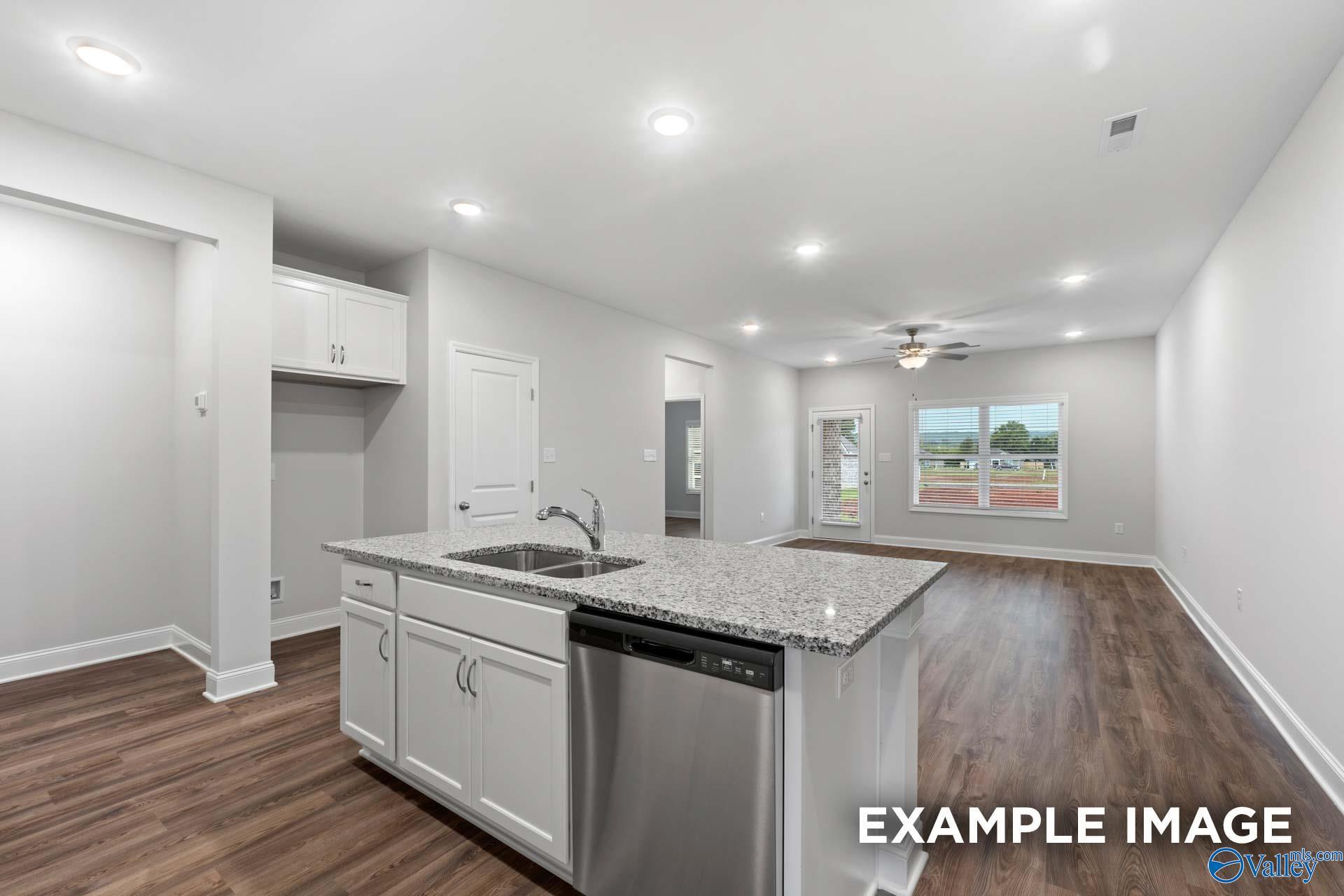 Bright open kitchen with granite island, stainless dishwasher, white cabinets, hardwood floors in Davidson Homes The Cumberland, Decatur AL