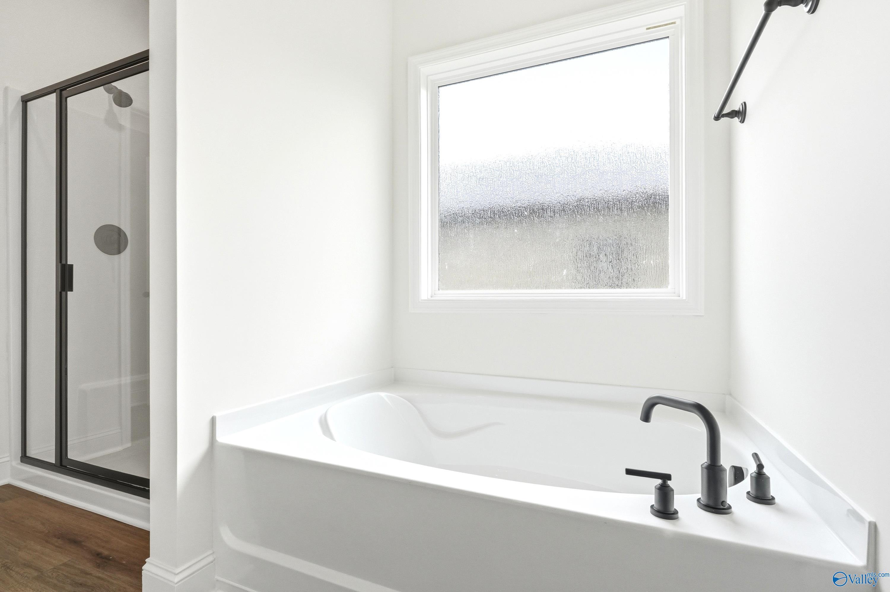 Modern master bathroom with soaking tub and separate shower in The Daphne C floor plan by Davidson Homes in Toney, Alabama.