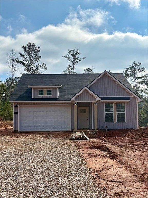 Modern 1-story 4-bedroom home with gray siding, 2-car garage, dormer window, and pine trees in Silver Oak, Cusseta, Alabama