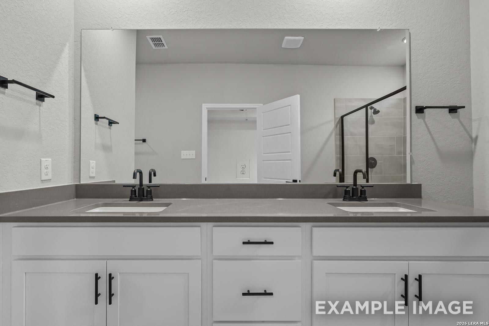 Modern bathroom with double vanity, quartz countertops, and matte black fixtures in The Glenwood E, Royal Crest, San Antonio.