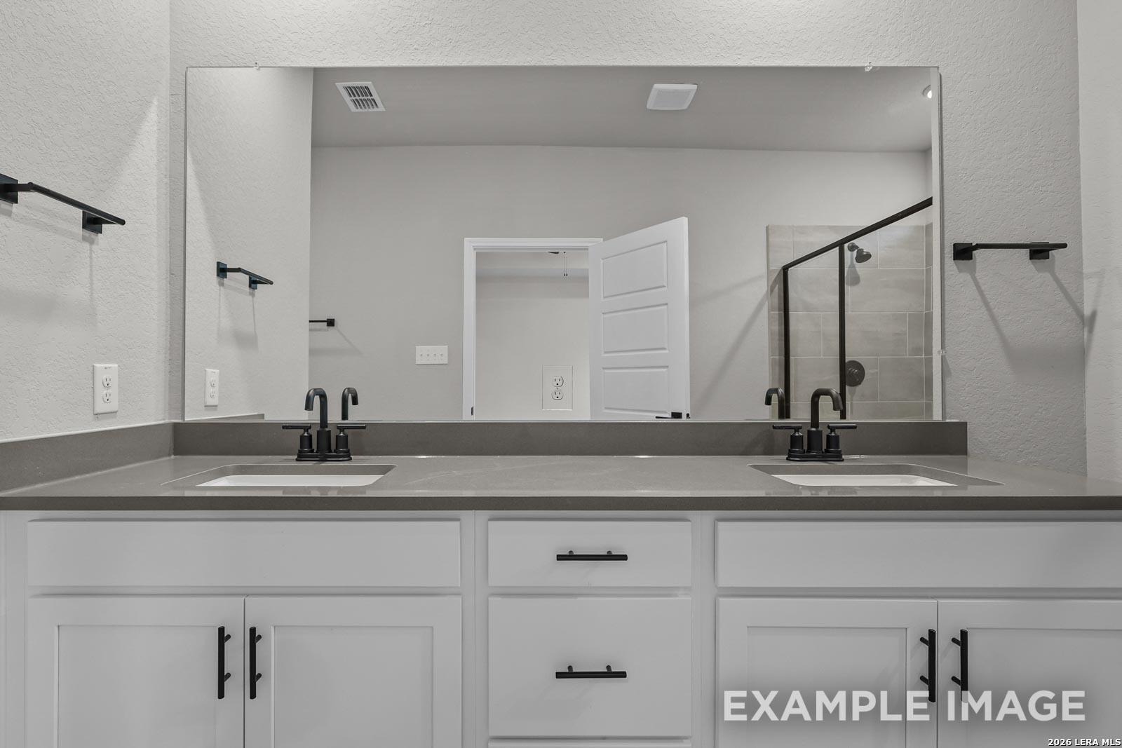 Modern bathroom with double vanity, quartz countertops, and matte black fixtures in The Glenwood E, Royal Crest, San Antonio.
