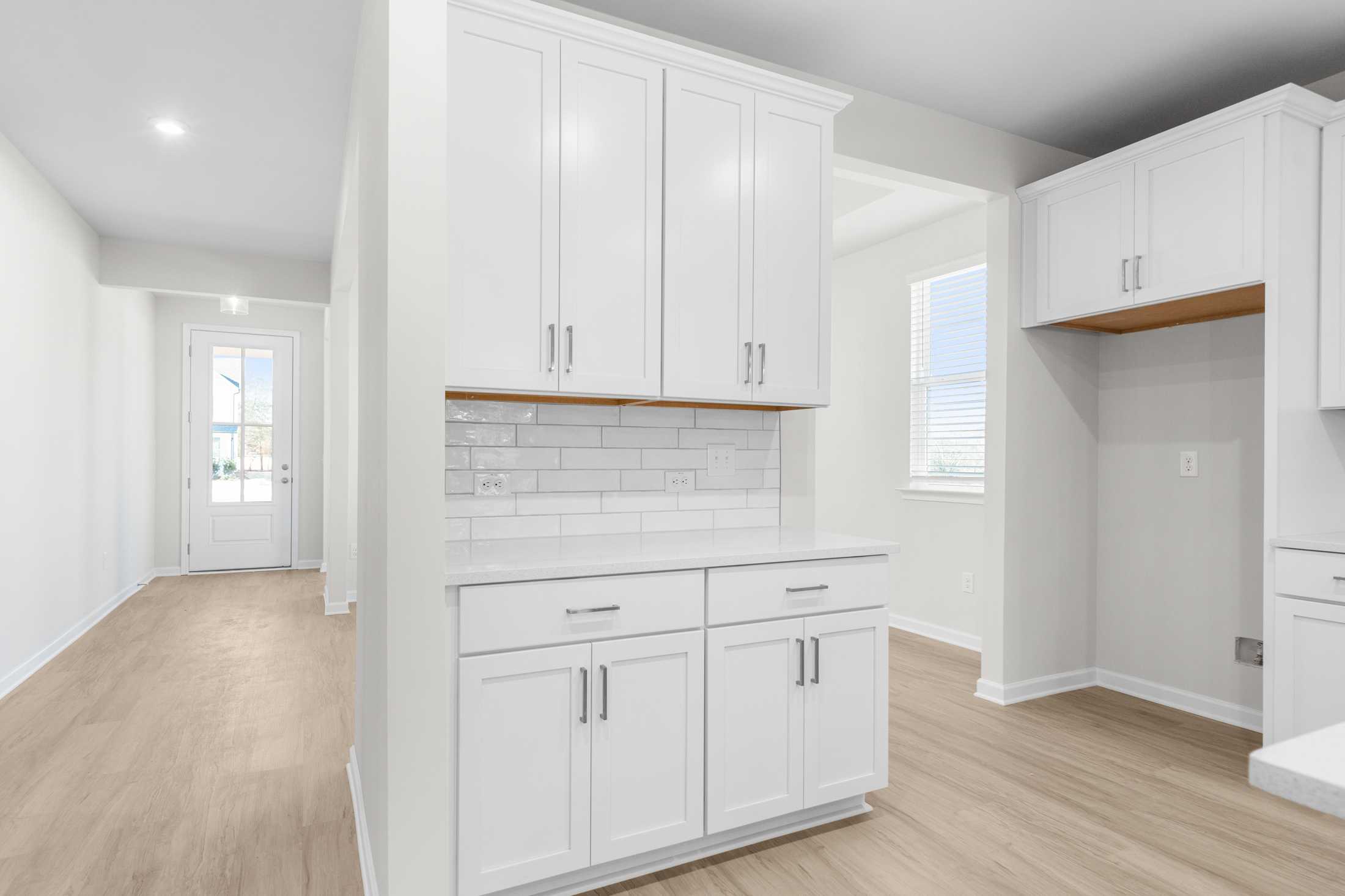 Modern kitchen in The Glenwood A featuring white shaker cabinets, subway tile backsplash, and light oak floors