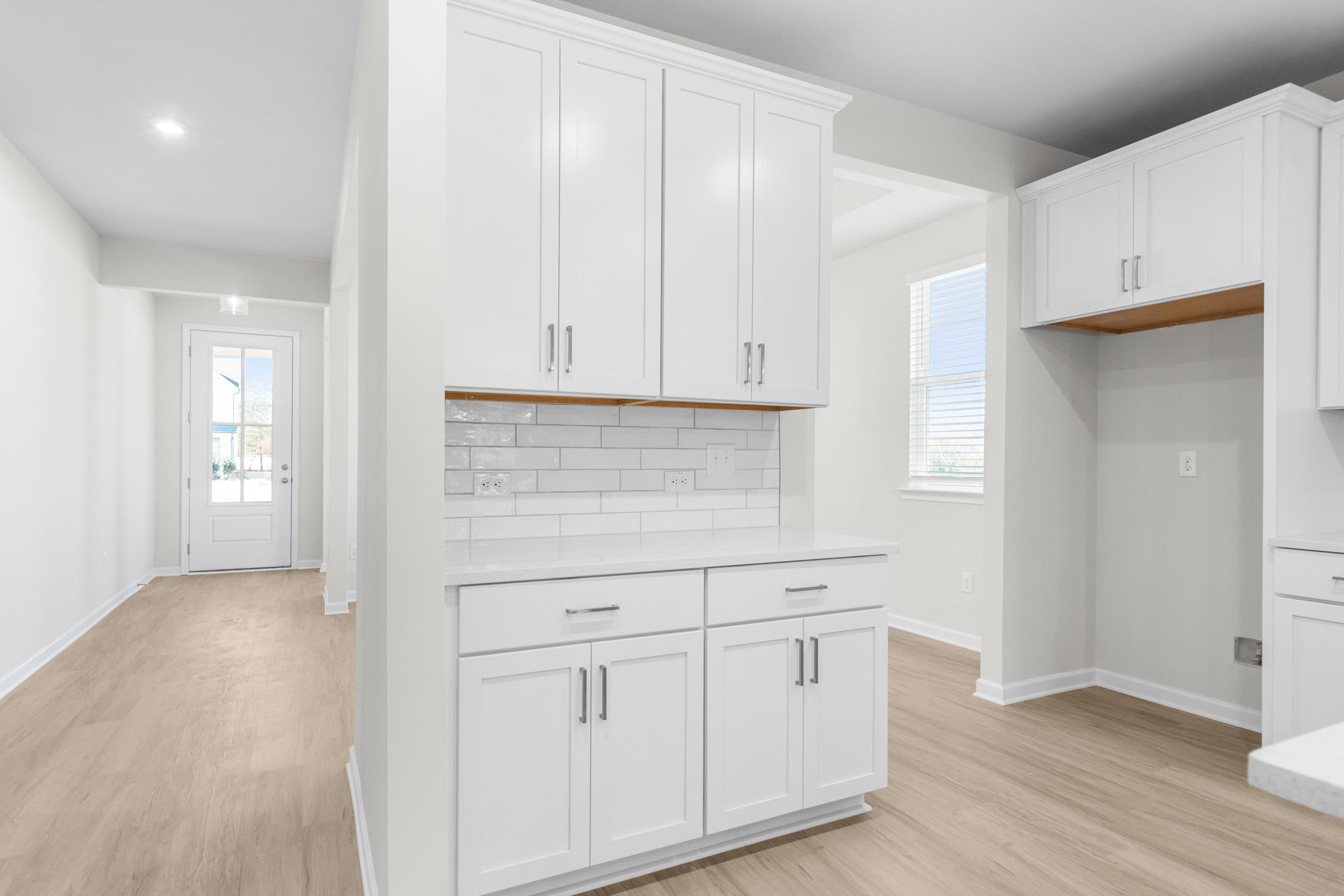 Modern kitchen in The Glenwood A featuring white shaker cabinets, subway tile backsplash, and light oak floors