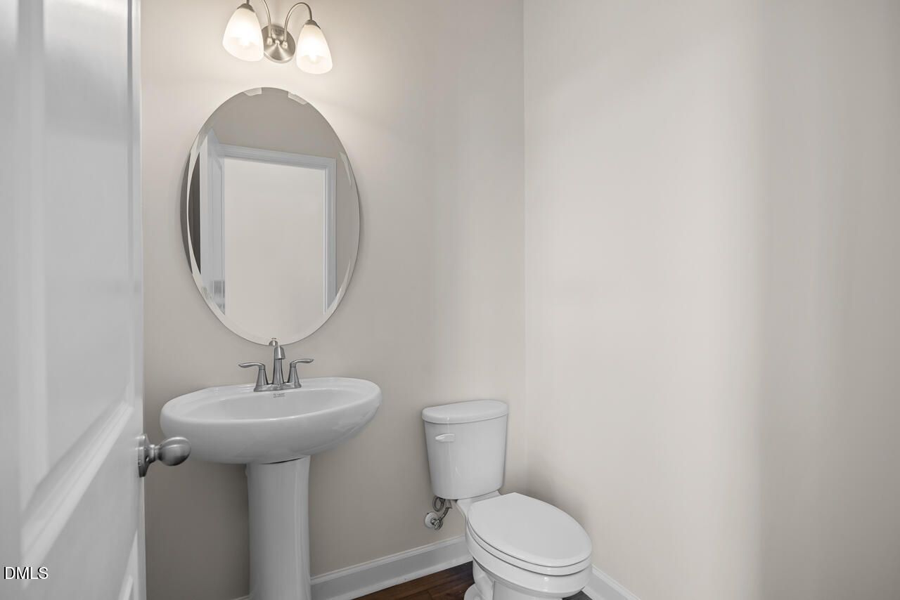 Powder room with pedestal sink, oval mirror, and brushed nickel sconce in Davidson Homes' Mitchell plan, Knightdale, NC