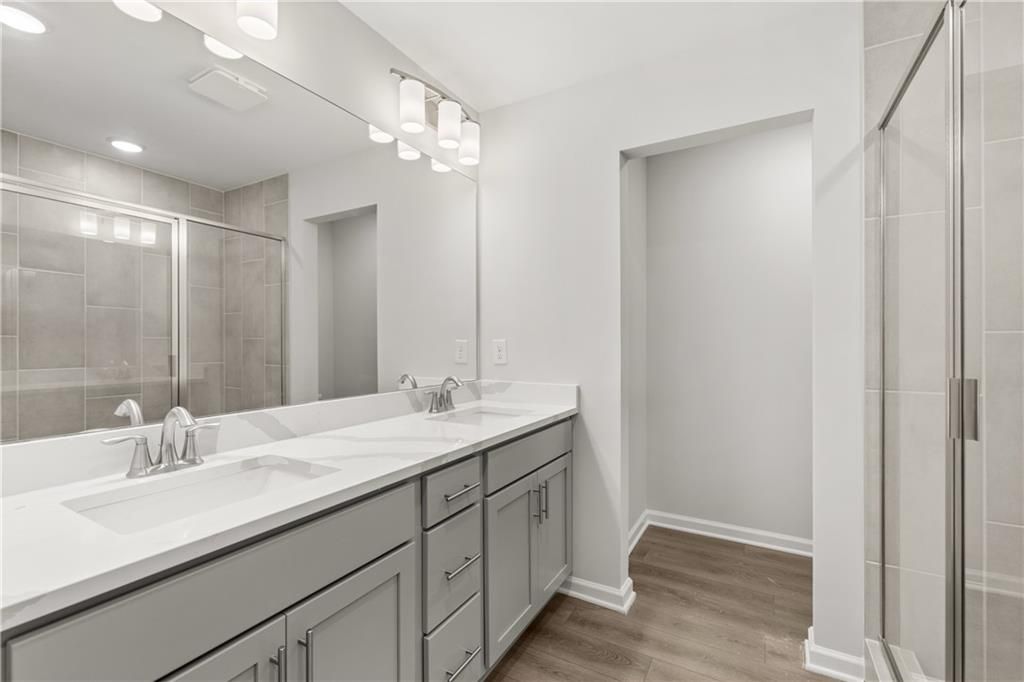 Modern bathroom with dual vanity, quartz countertops, and glass shower in The Burton A floor plan, The Bluffs, Canton, GA.