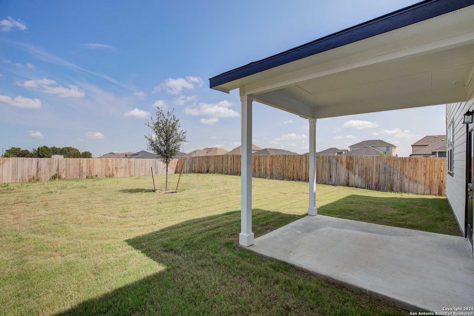 Covered back patio with white columns overlooking fenced grassy yard in Davidson Homes The Douglas D, Hannah Heights, Seguin, Texas