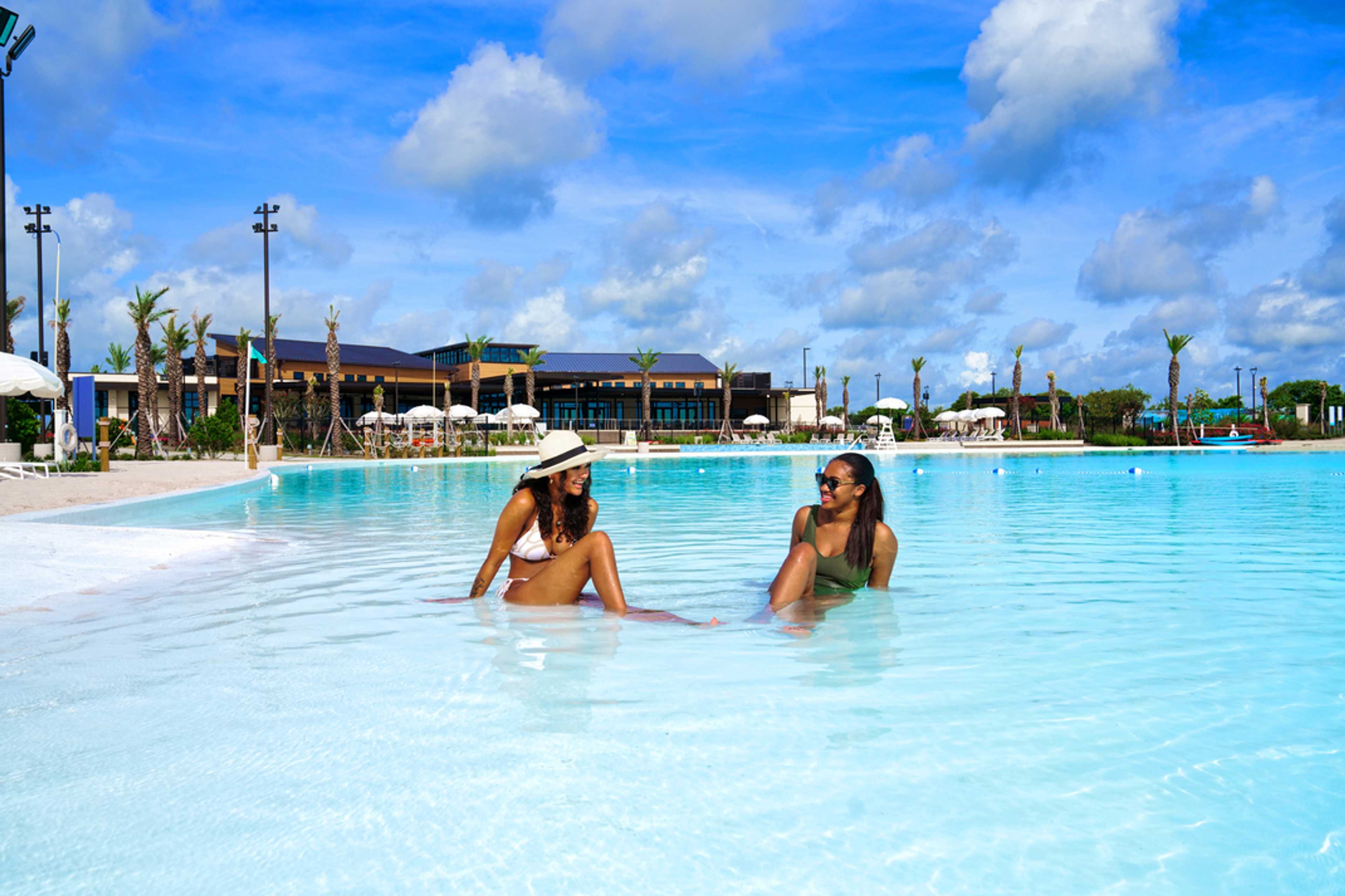 Resort-style infinity pool at Lago Mar in Texas City TX with women relaxing amid palms and cabanas