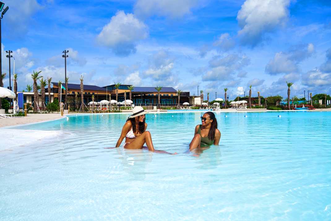 Resort-style infinity pool at Lago Mar in Texas City TX with women relaxing amid palms and cabanas