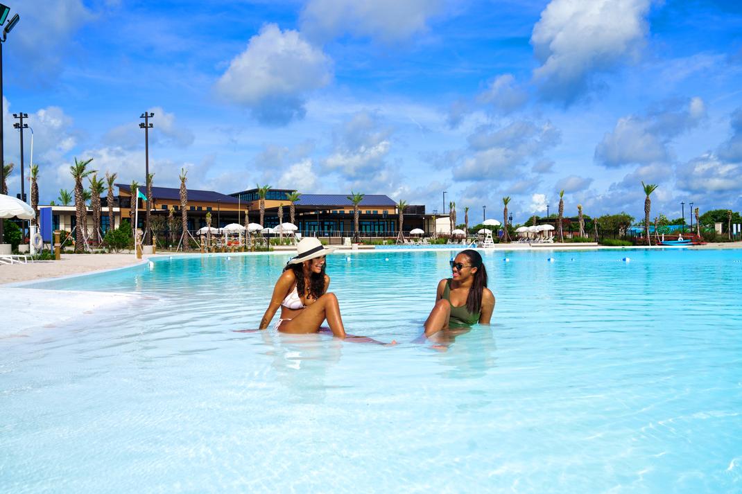 Resort-style infinity pool at Lago Mar in Texas City TX with women relaxing amid palms and cabanas