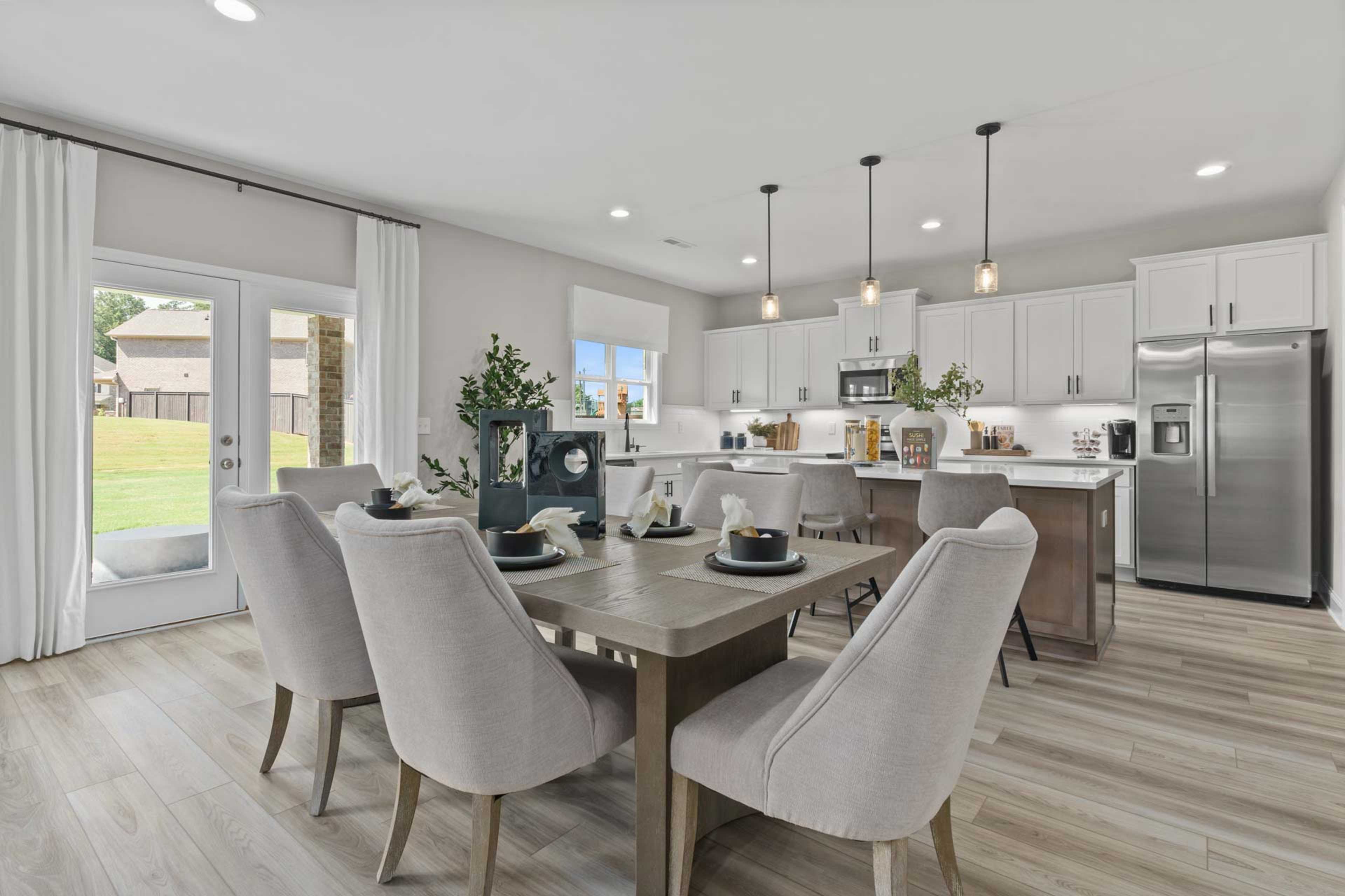Spacious open-concept kitchen and dining area at Creek Grove in New Market Alabama with white cabinets hardwood floors and French doors