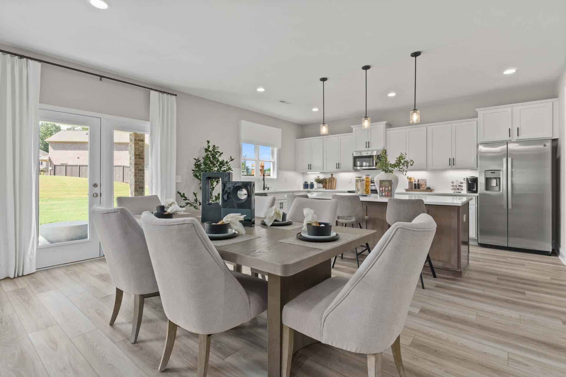 Spacious open-concept kitchen and dining area at Creek Grove in New Market Alabama with white cabinets hardwood floors and French doors