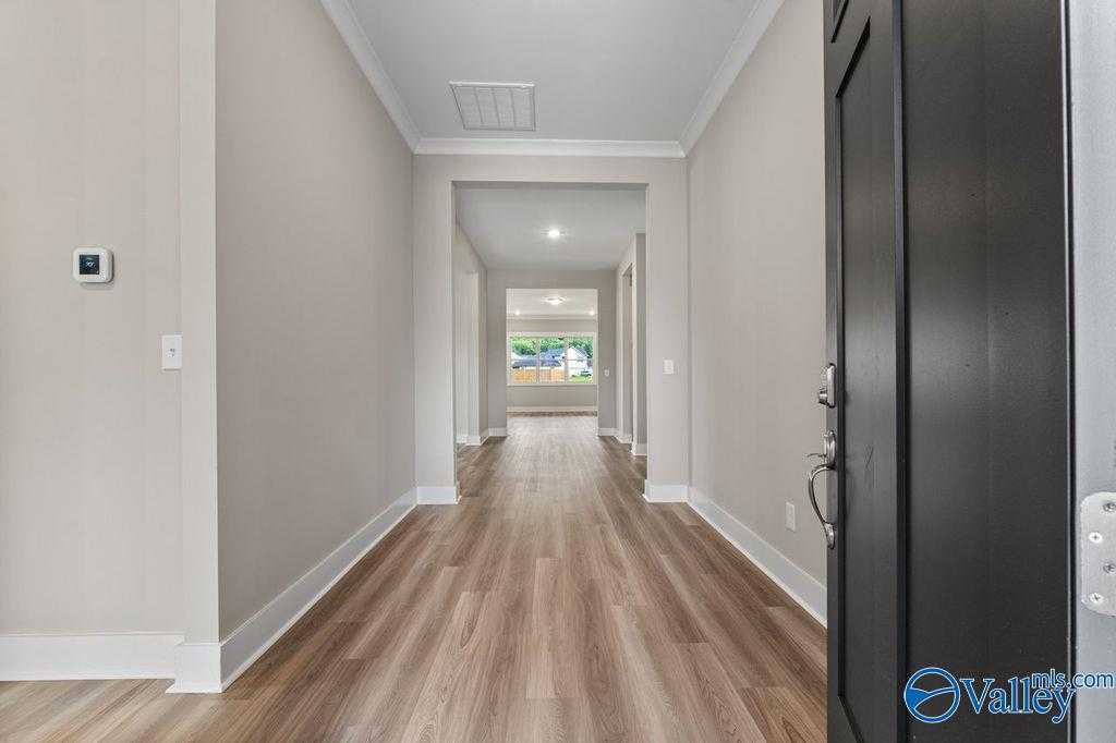Spacious entry hallway with hardwood floors, light gray walls, and open views in The Oxford 5-bedroom home by Evermore Homes, Owens Cross Roads, Alabama