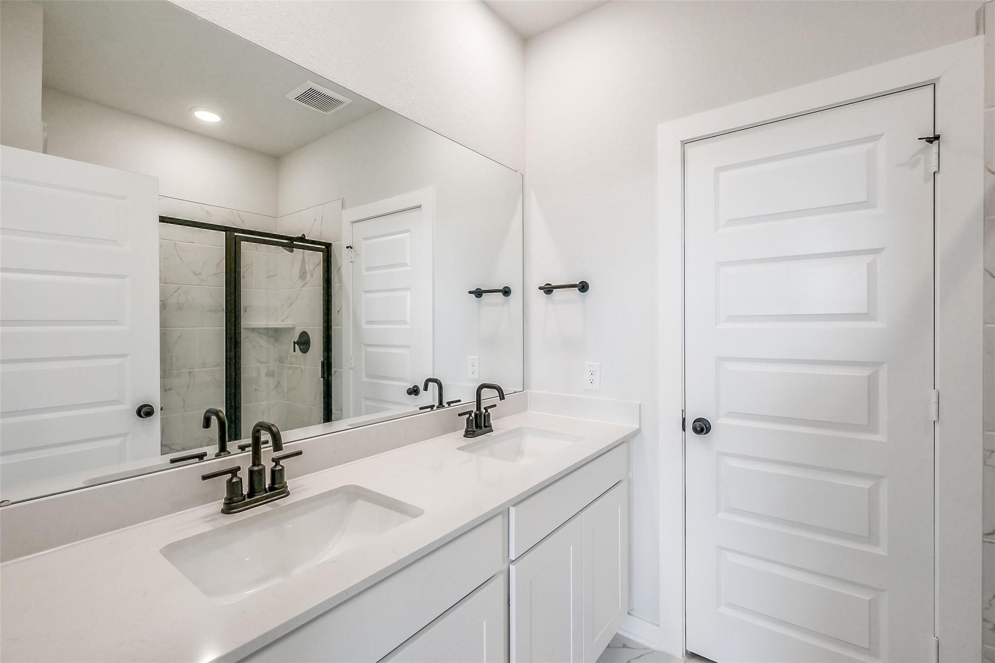 Modern double vanity master bathroom with white quartz counters, glass shower in Davidson Homes San Marcos E, Beasley Texas