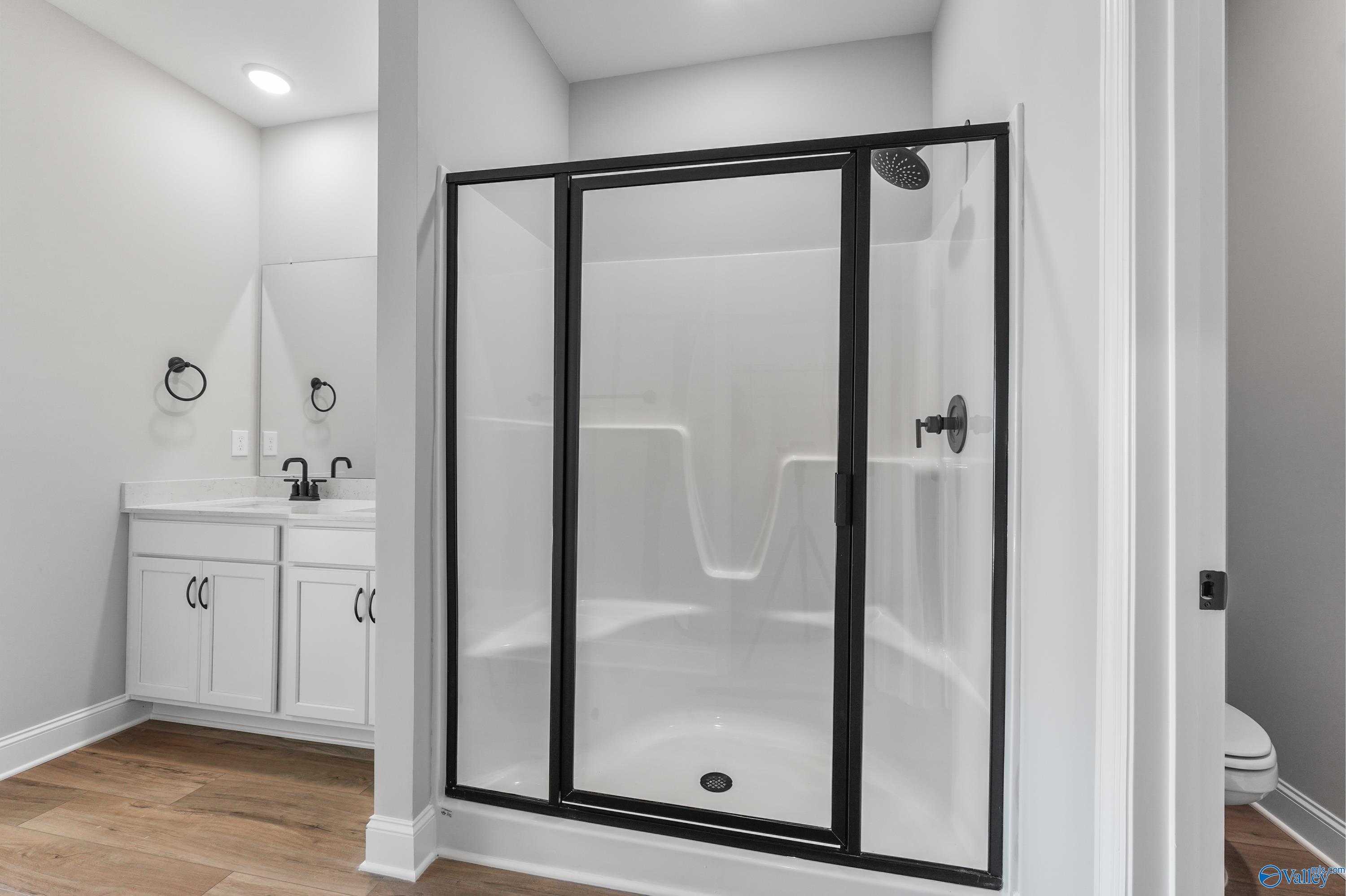Modern master bathroom with frameless glass shower, white shaker vanity, and walk-in design in Davidson Homes The Daphne C, Hazel Green, AL