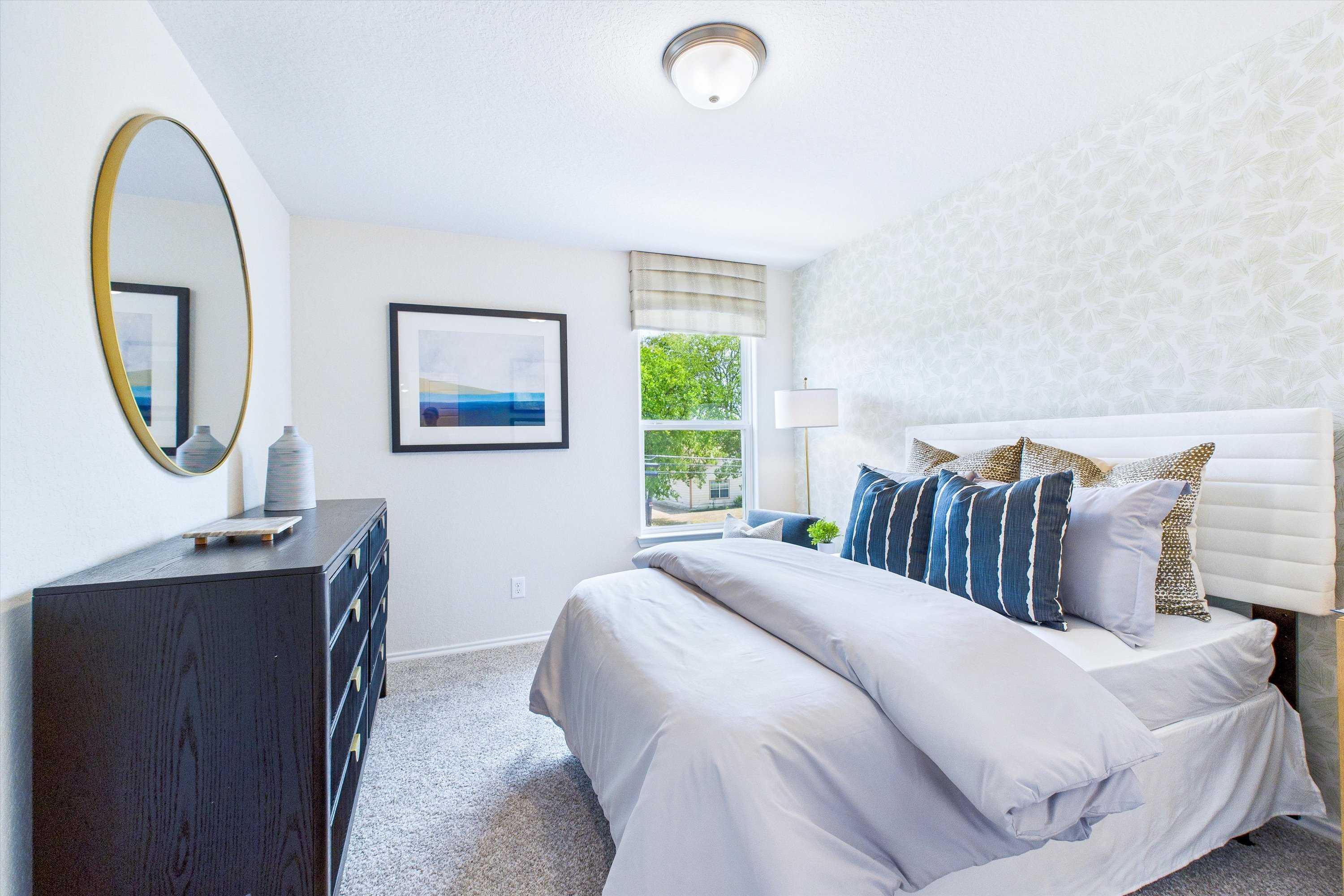 Modern bedroom at Cedar Heights San Antonio TX by Davidson Homes with king bed neutral walls gold mirror seascape art and plush pillows