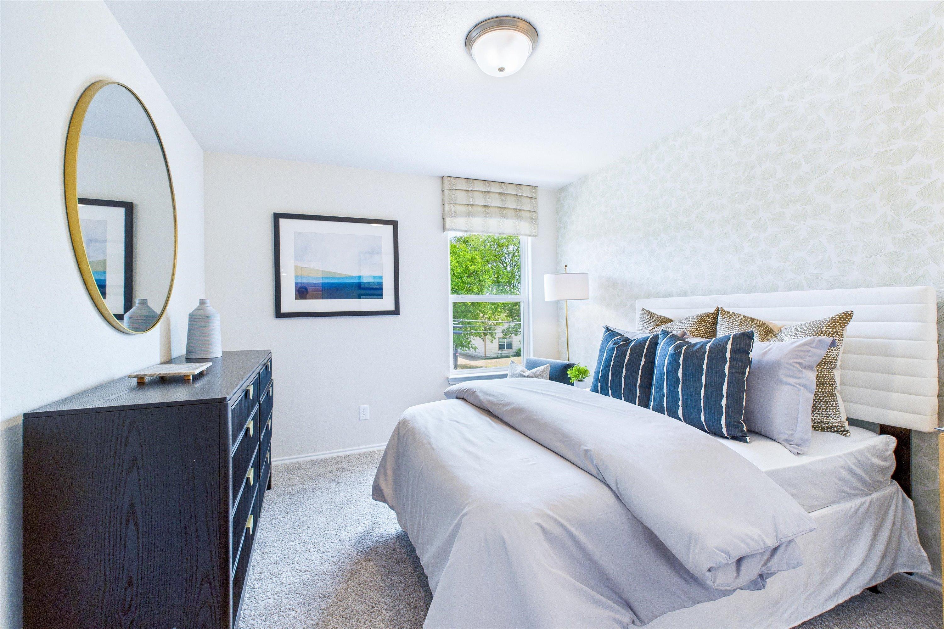 Modern bedroom at Cedar Heights San Antonio TX by Davidson Homes with king bed neutral walls gold mirror seascape art and plush pillows