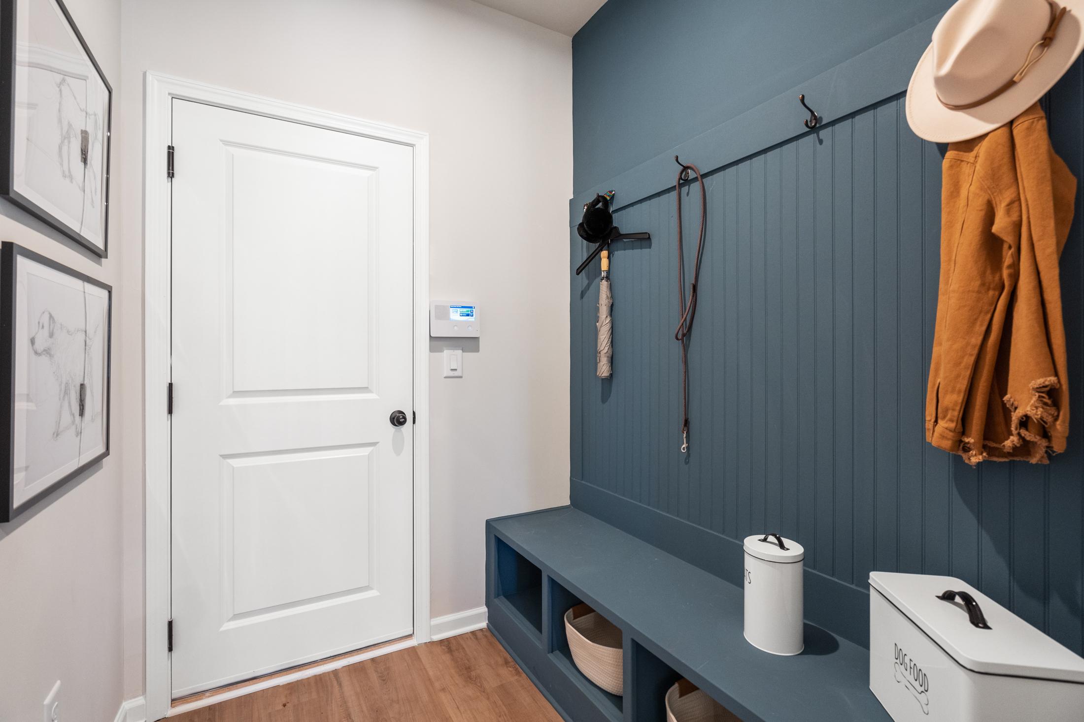 Cozy mudroom in The Marion A with navy shiplap wall, built-in bench, coat hooks, hat rack, and storage baskets by Davidson Homes
