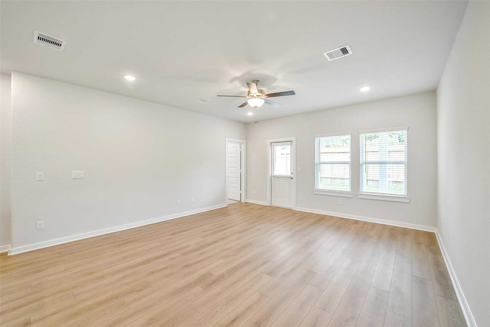 Bright bedroom featuring hardwood floors, ceiling fan, large windows, and glass patio door in Davidson Homes The Blanco E, Magnolia, Texas