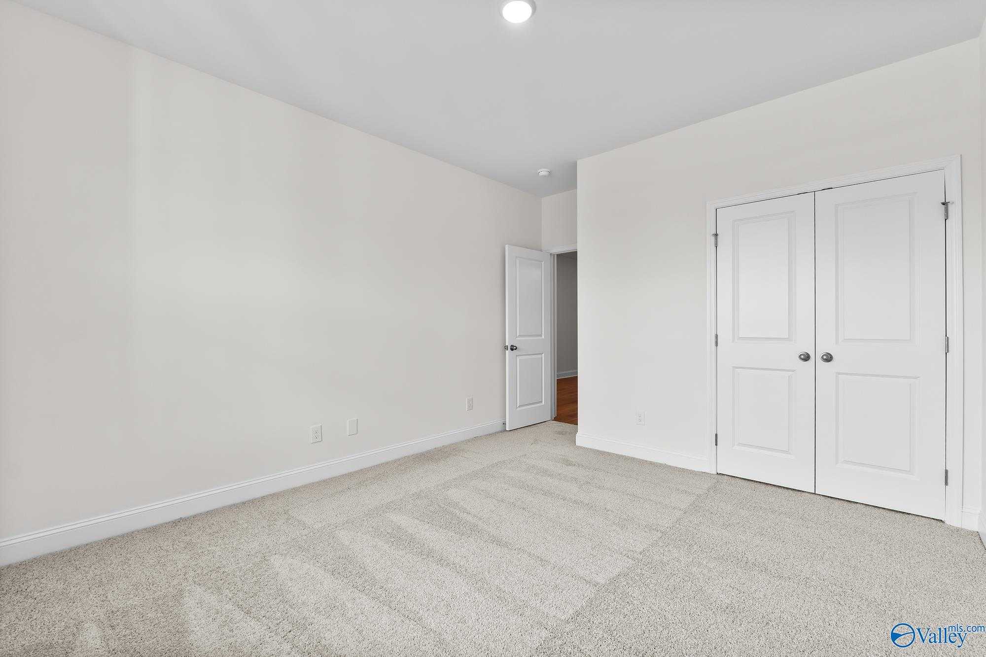 Spacious carpeted bedroom with double-door closet and white walls in Davidson Homes The Harrison, Meridianville, Alabama