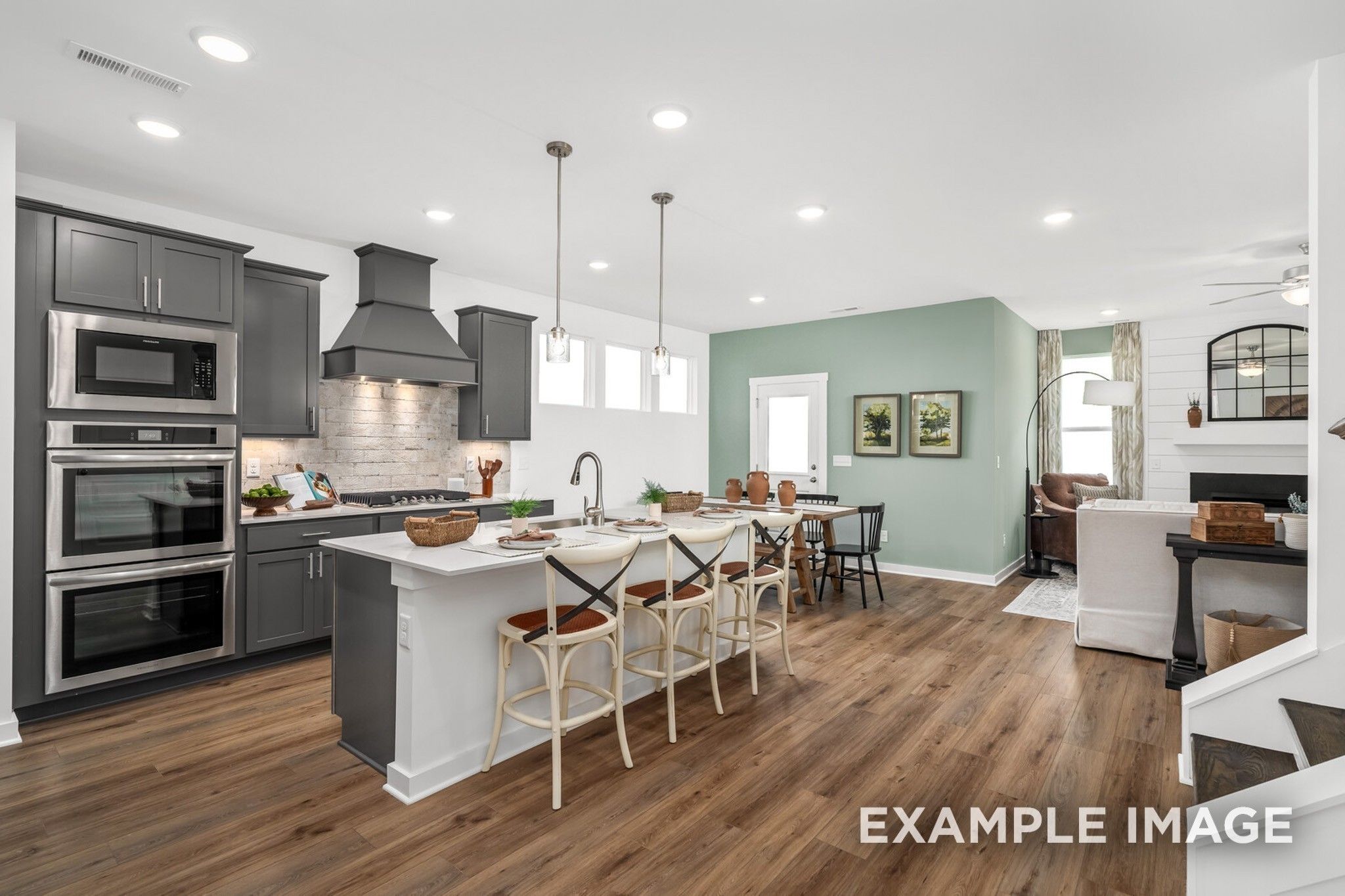 Open-concept kitchen with dark cabinets and island in The Ash A floor plan at Woods Crossing, Gallatin, Tennessee.