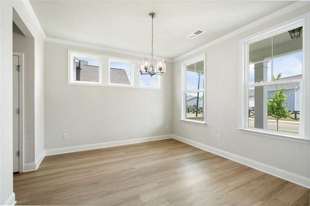 Bright dining room with chandelier, large windows, and hardwood floors in The Willow D home at Wehunt Meadows, Hoschton, Georgia