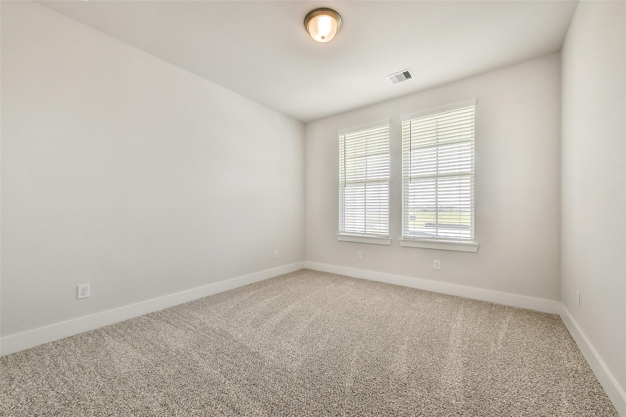 Bright empty bedroom featuring white walls, beige carpet, double blinds-covered windows in Davidson Homes The Victoria A, Lago Mar, Texas City
