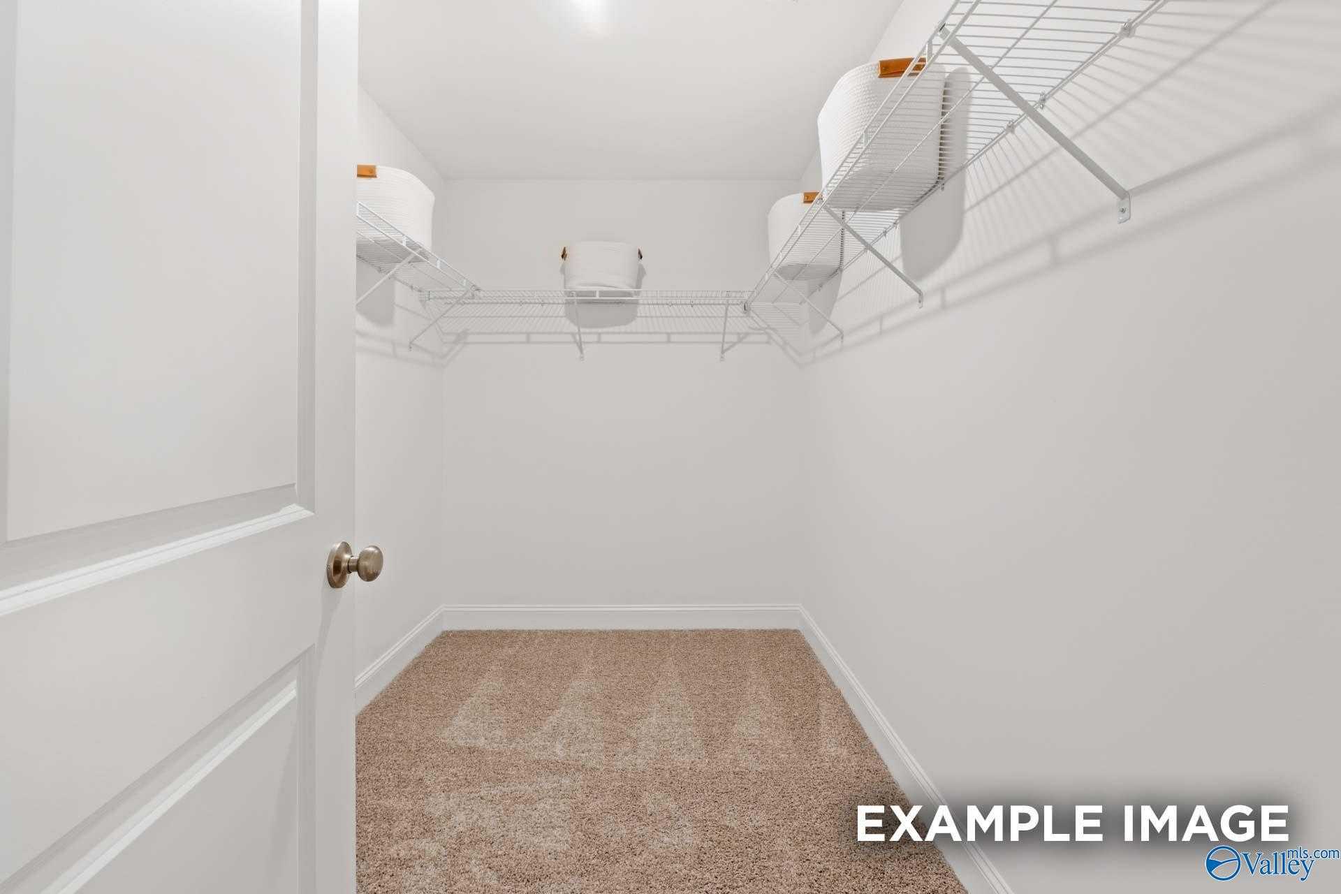 Spacious walk-in closet with wire shelving and orange storage bins in Davidson Homes The Camden B, Huntsville, Alabama