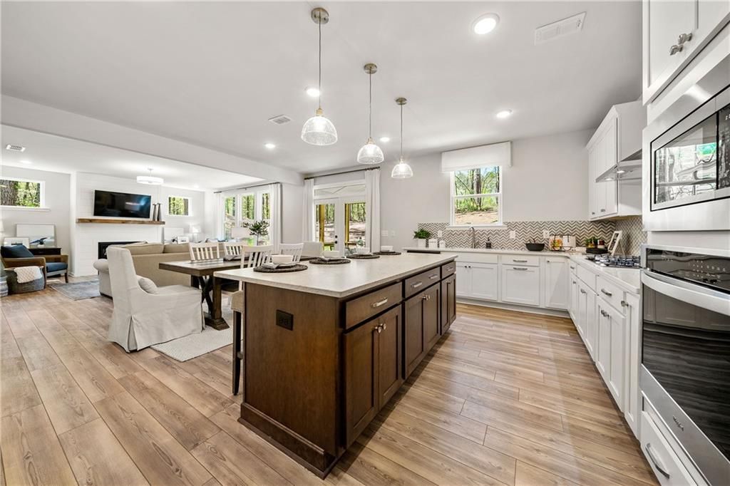 Open-concept kitchen with white cabinets, wood island, stainless appliances, and adjacent living area in Davidson Homes Willow B, Dallas, GA