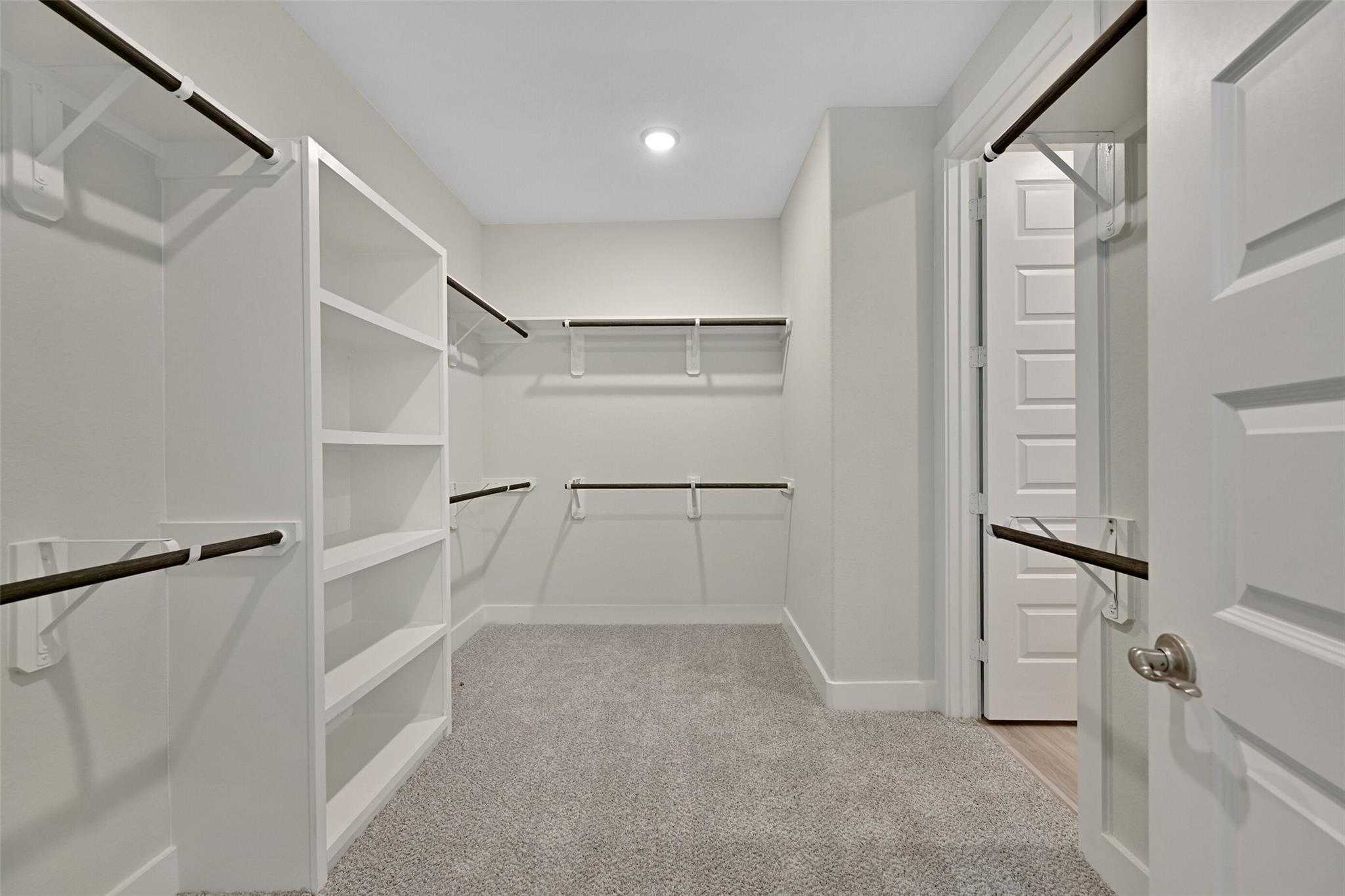 Spacious walk-in closet with white built-in shelves and hanging rods in Davidson Homes The Edward A, Lago Mar, Texas City