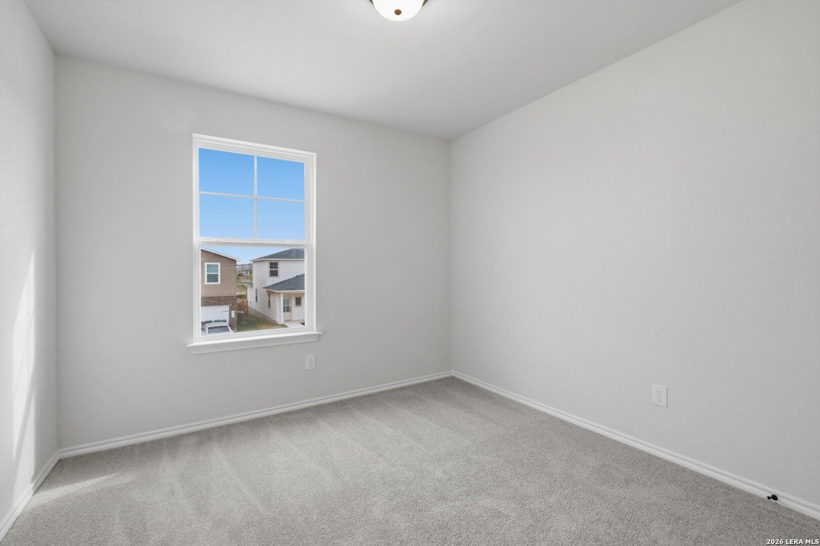 Bright secondary bedroom with light gray walls, plush carpet, and neighborhood view window in Davidson Homes The Blanco C, San Antonio