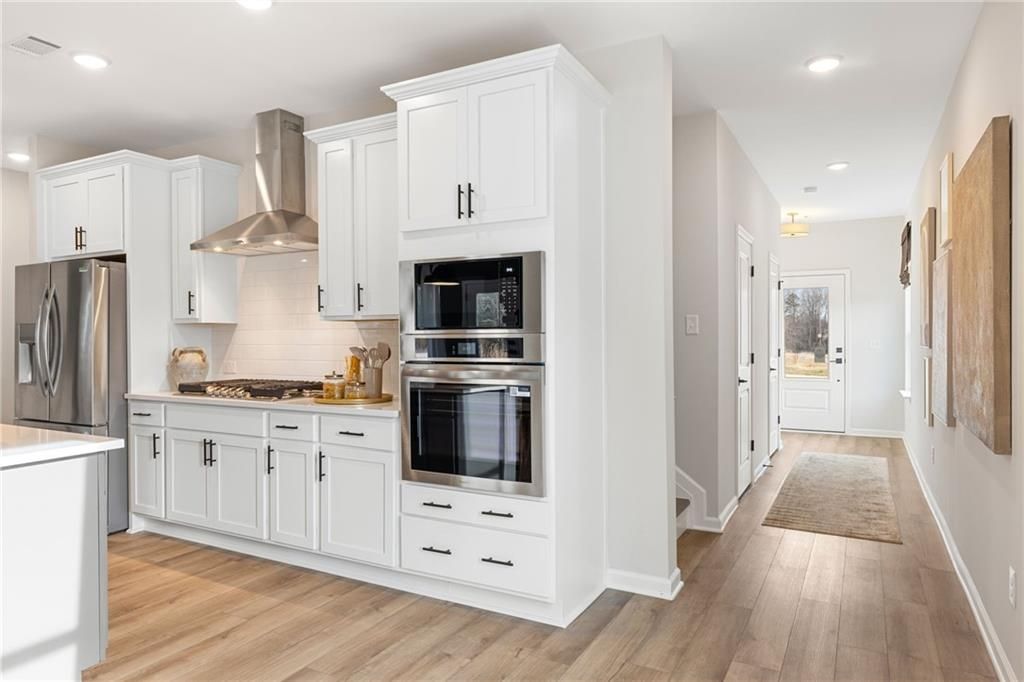 Modern white kitchen with stainless steel appliances and wall oven in The Rabun B floor plan at The Bluffs, Canton, GA.