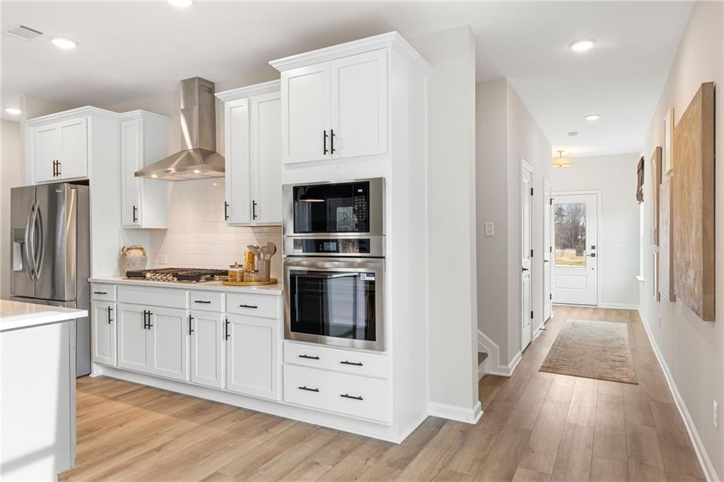 Modern white kitchen with stainless steel appliances and wall oven in The Rabun B floor plan at The Bluffs, Canton, GA.
