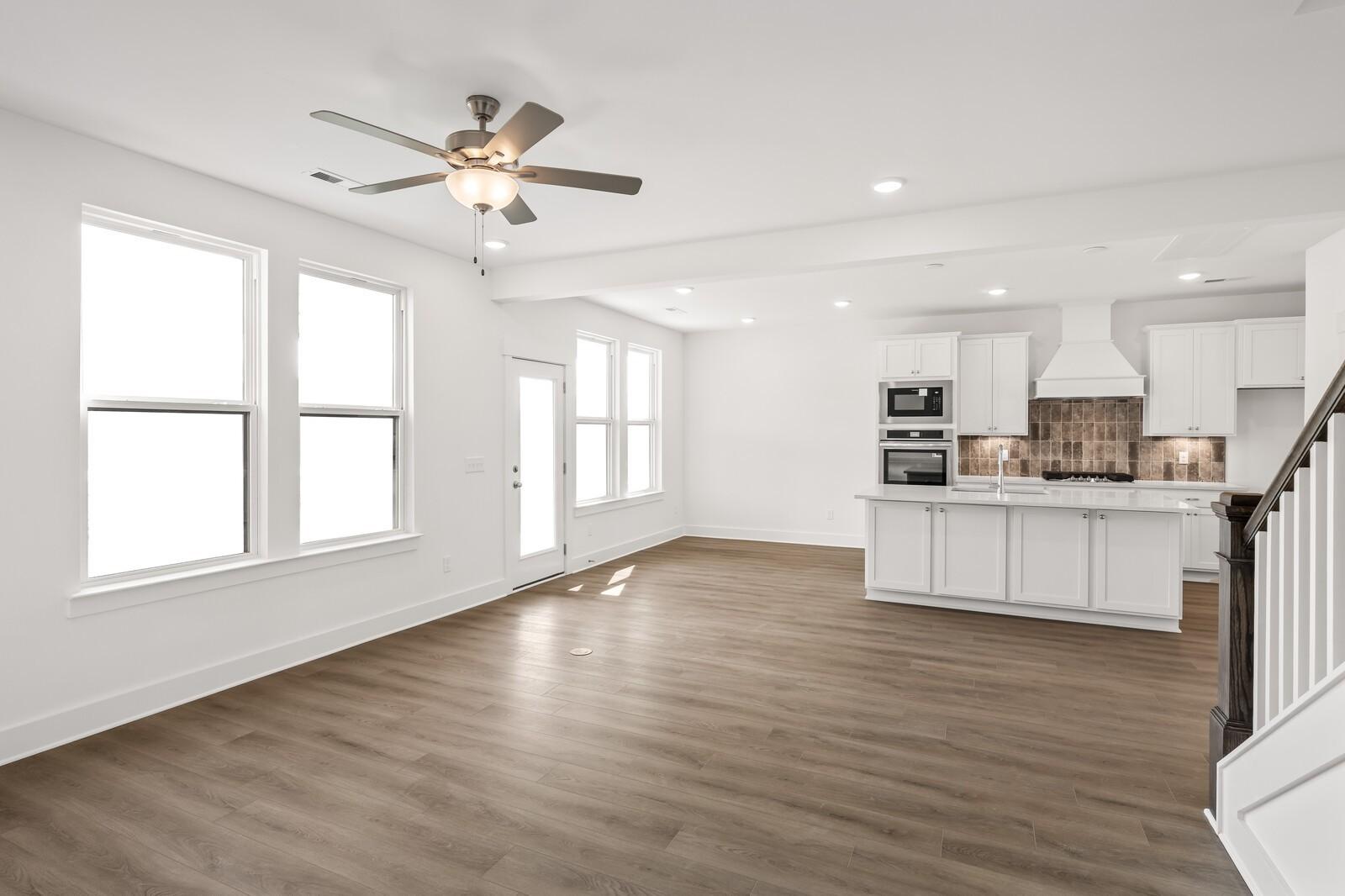 Open-concept living-kitchen with hardwood floors, white cabinets, stainless appliances, and staircase in The Willow D, Mt. Juliet, TN