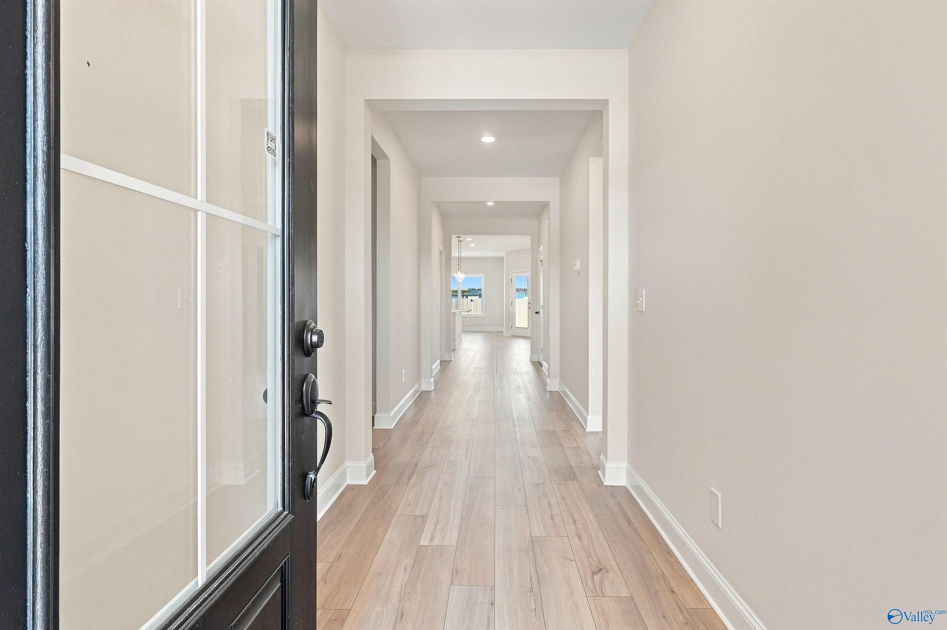 Bright, open foyer and hallway with light wood-style flooring in The Everett B floor plan by Davidson Homes in Toney, AL.