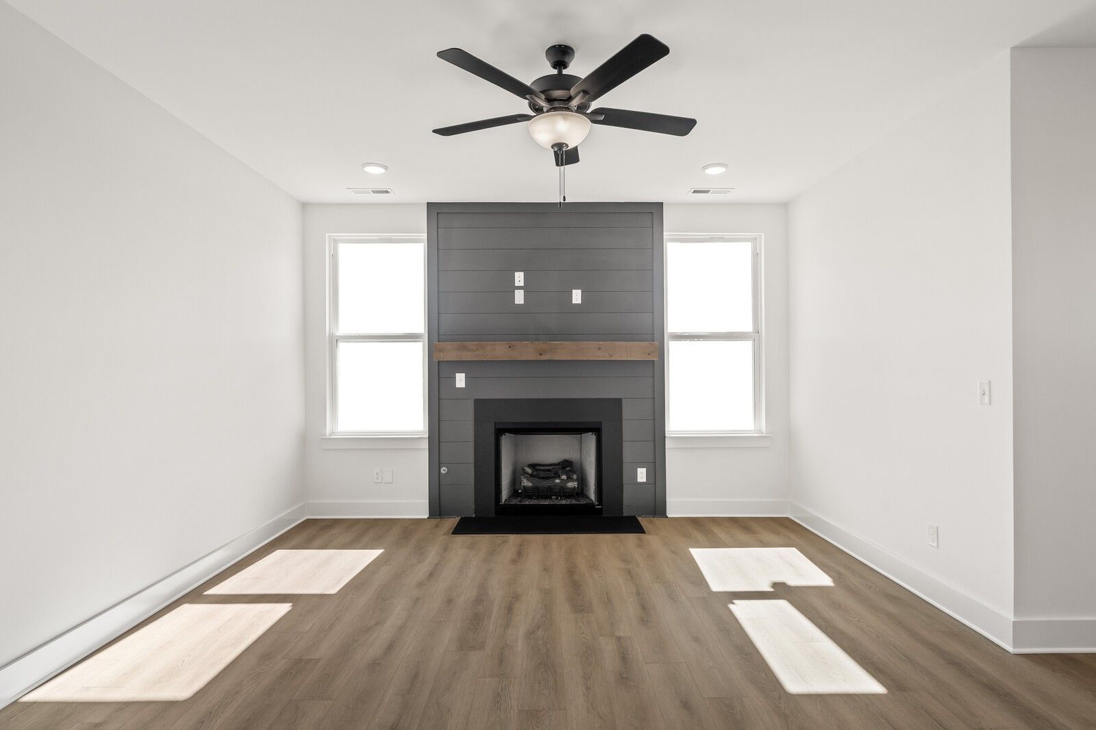 Cozy living room with modern gas fireplace, gray shiplap accent wall, hardwood floors in Davidson Homes The Ash A, Gallatin, TN