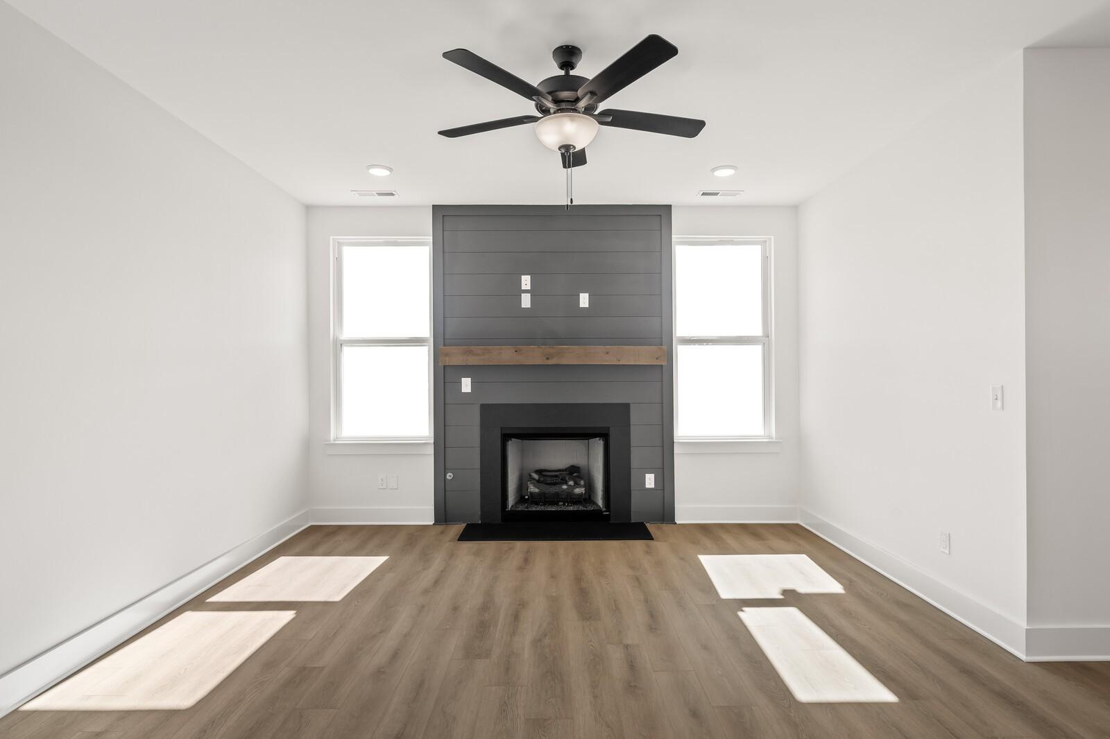 Cozy living room with modern gas fireplace, gray shiplap accent wall, hardwood floors in Davidson Homes The Ash A, Gallatin, TN