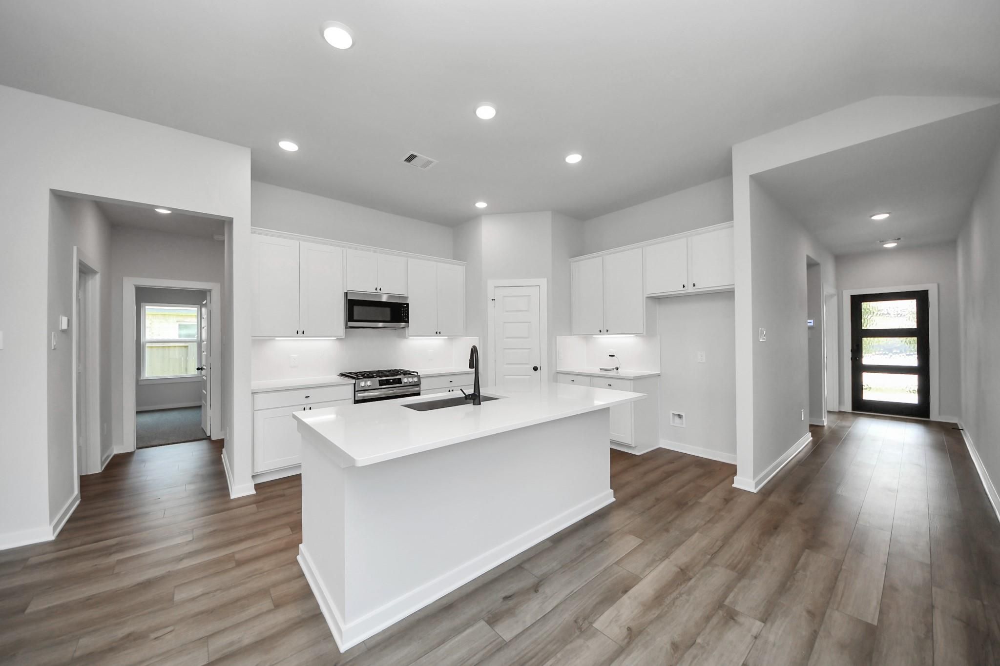 Modern open-concept kitchen with white cabinets and center island in The Riviera C floor plan, River Ranch Meadows, Dayton.