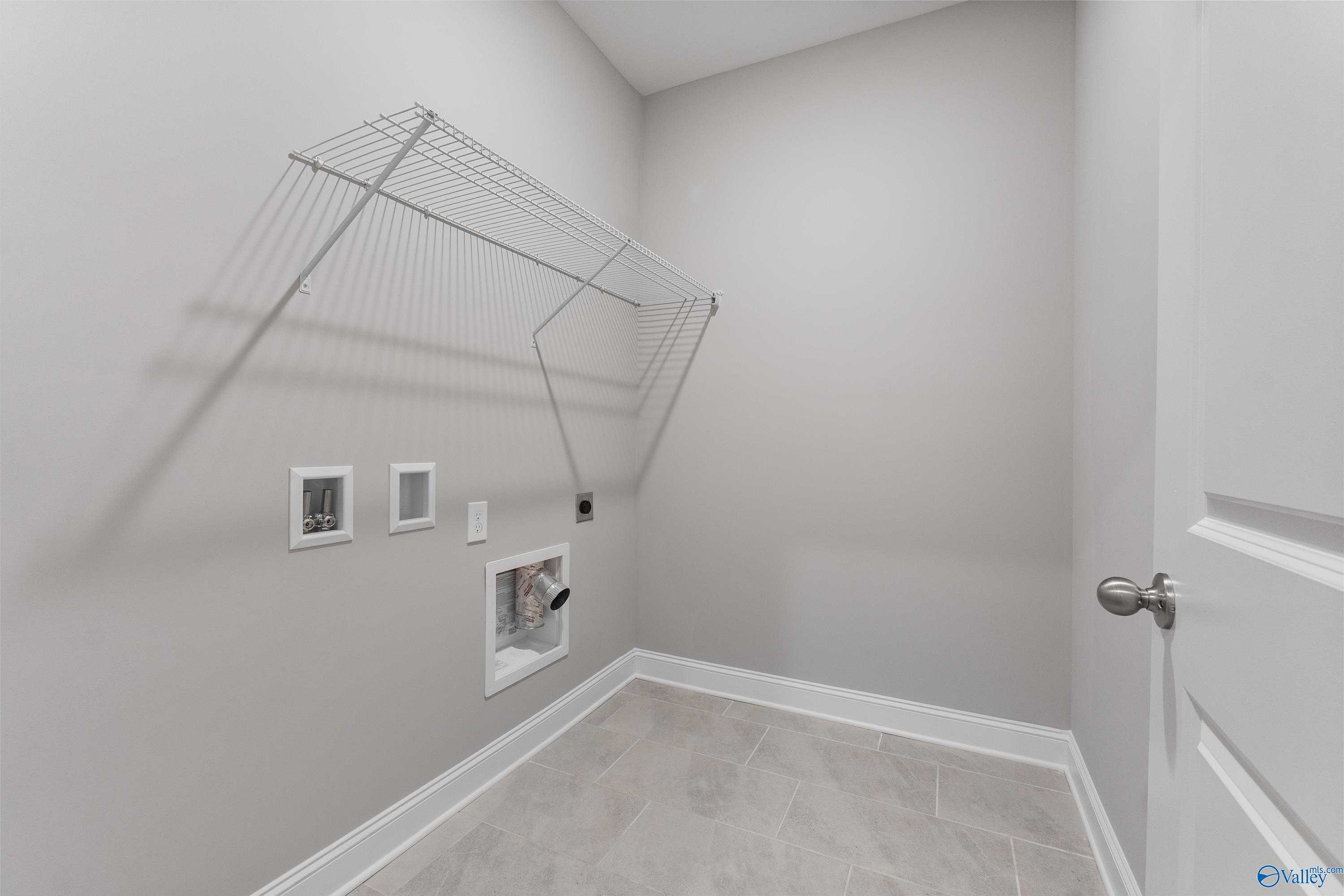 Modern laundry room with wire drying rack, washer dryer hookups, and gray tile floor in Davidson Homes The Rockford, Harvest, Alabama
