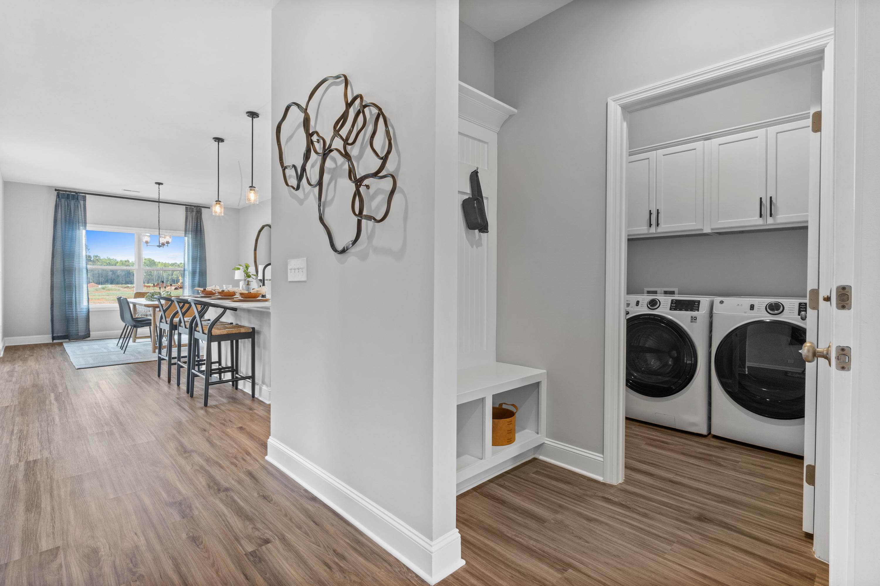 Spacious laundry room and mudroom in Wood Trail home, Toney Alabama with washer dryer, hardwood floors, and adjacent dining area