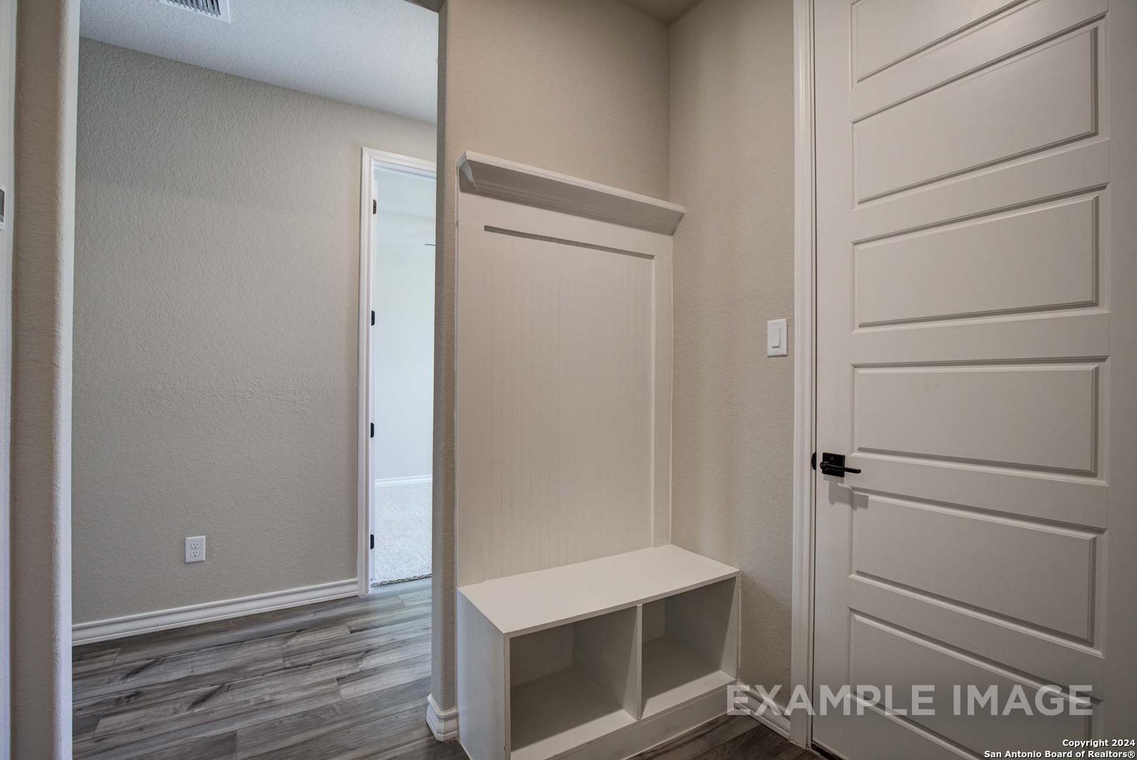 Functional mudroom with built-in white bench, storage cubbies, and coat shelf in Davidson Homes The Rockford G, Ladera San Antonio