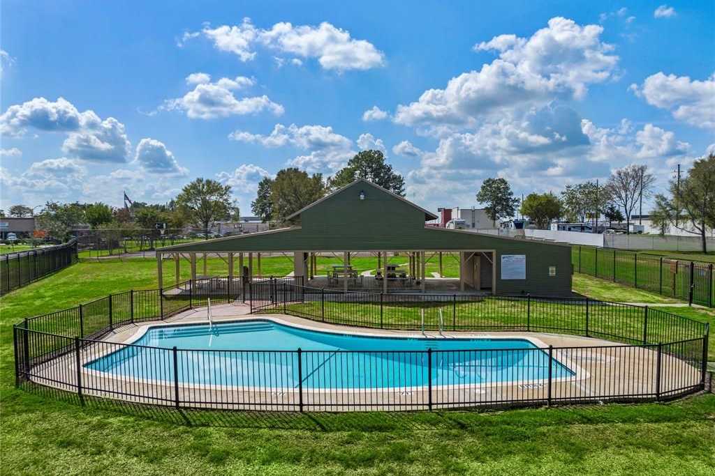 Community pool at Windmill Estates in Magnolia Texas with kidney-shaped design, green pavilion, and fenced grassy surround