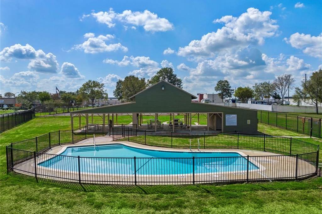 Community pool at Windmill Estates in Magnolia Texas with kidney-shaped design, green pavilion, and fenced grassy surround