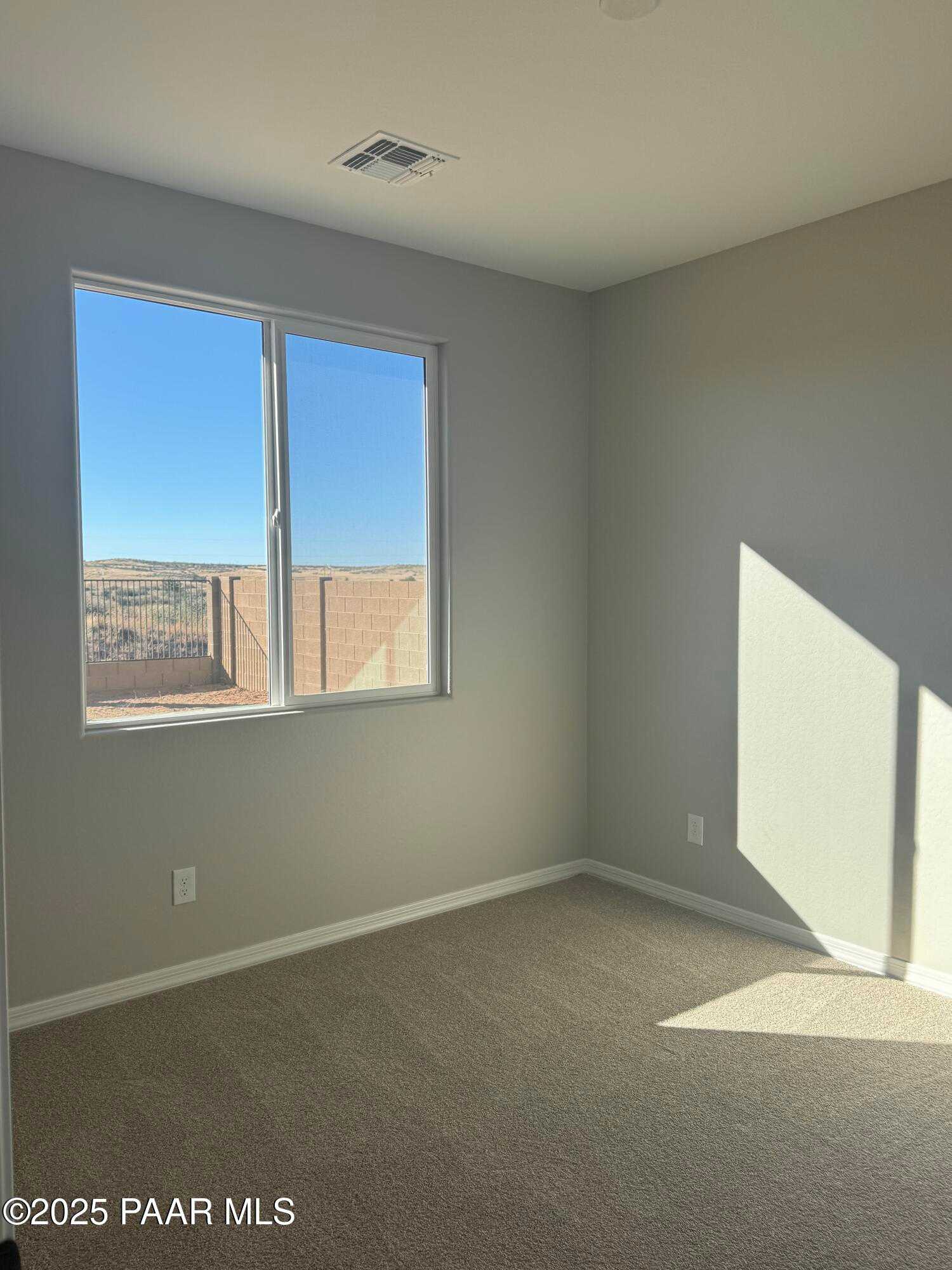 Bright bedroom with light gray walls, large window showcasing desert view, and beige carpet in Davidson Homes The Monarch E, Prescott, Arizona