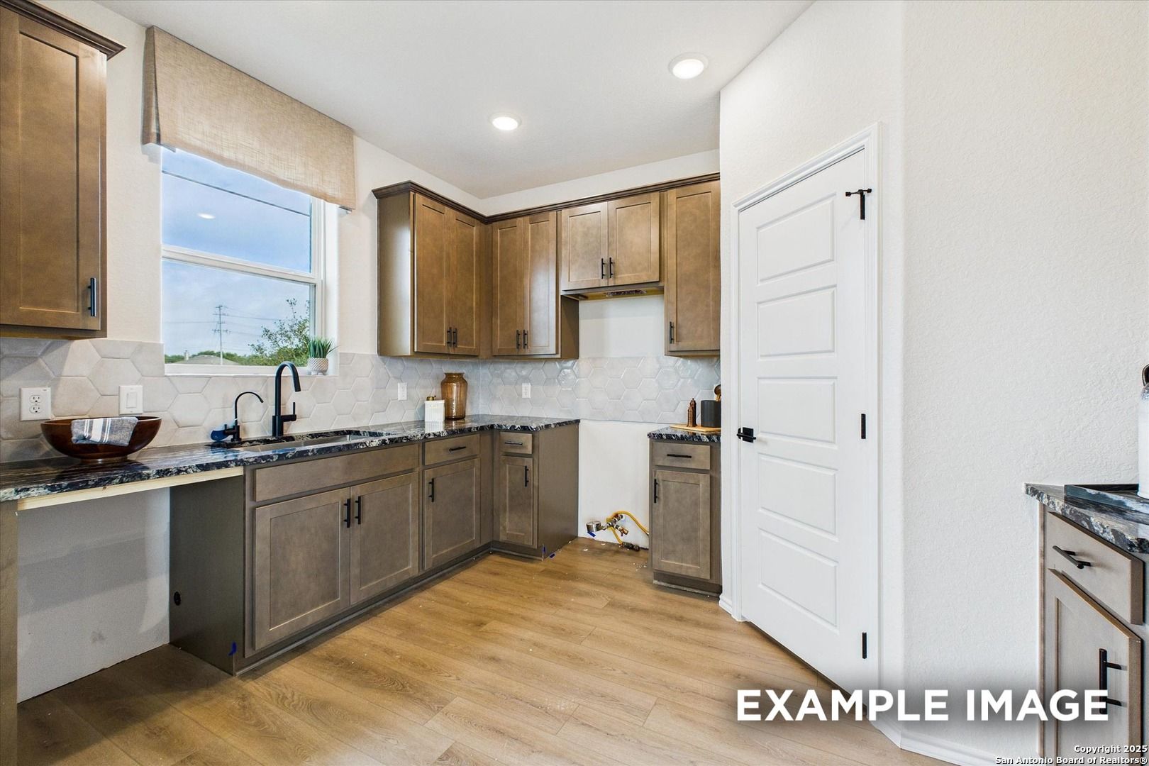 Contemporary kitchen with taupe shaker cabinets, dark granite counters, subway tile backsplash in Davidson Homes The Florence C, San Antonio