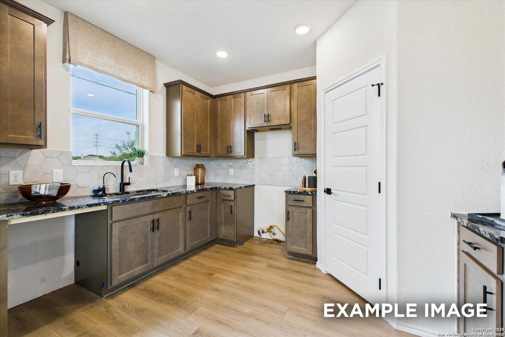 Contemporary kitchen with taupe shaker cabinets, dark granite counters, subway tile backsplash in Davidson Homes The Florence C, San Antonio