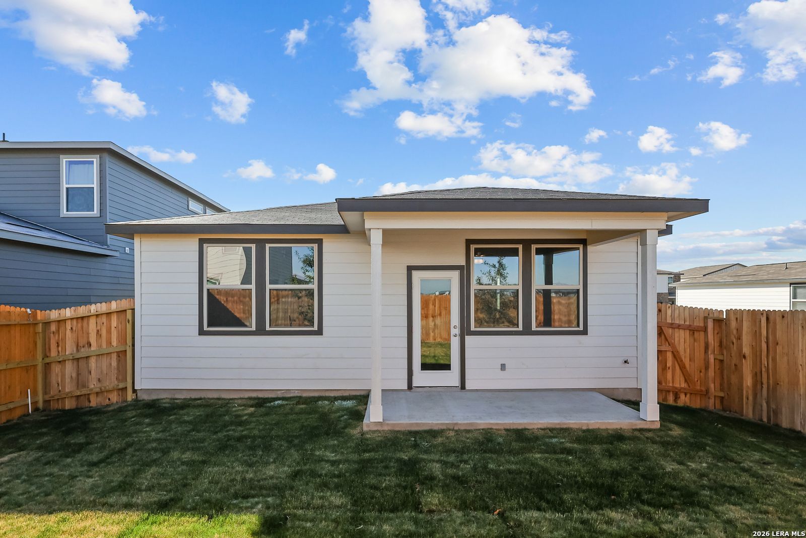 Covered back patio with glass door and windows on single-story The Frio B home in Applewhite Meadows, San Antonio, Texas